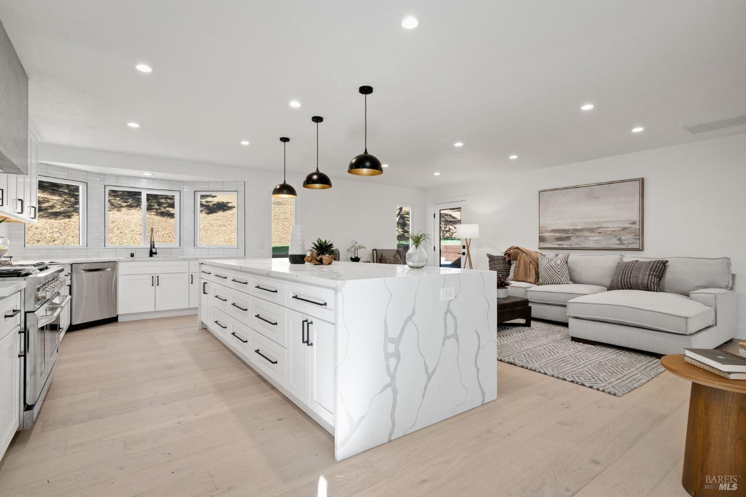 a large white kitchen with a large counter top and stainless steel appliances