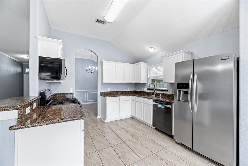 a kitchen with granite countertop a refrigerator and a stove top oven