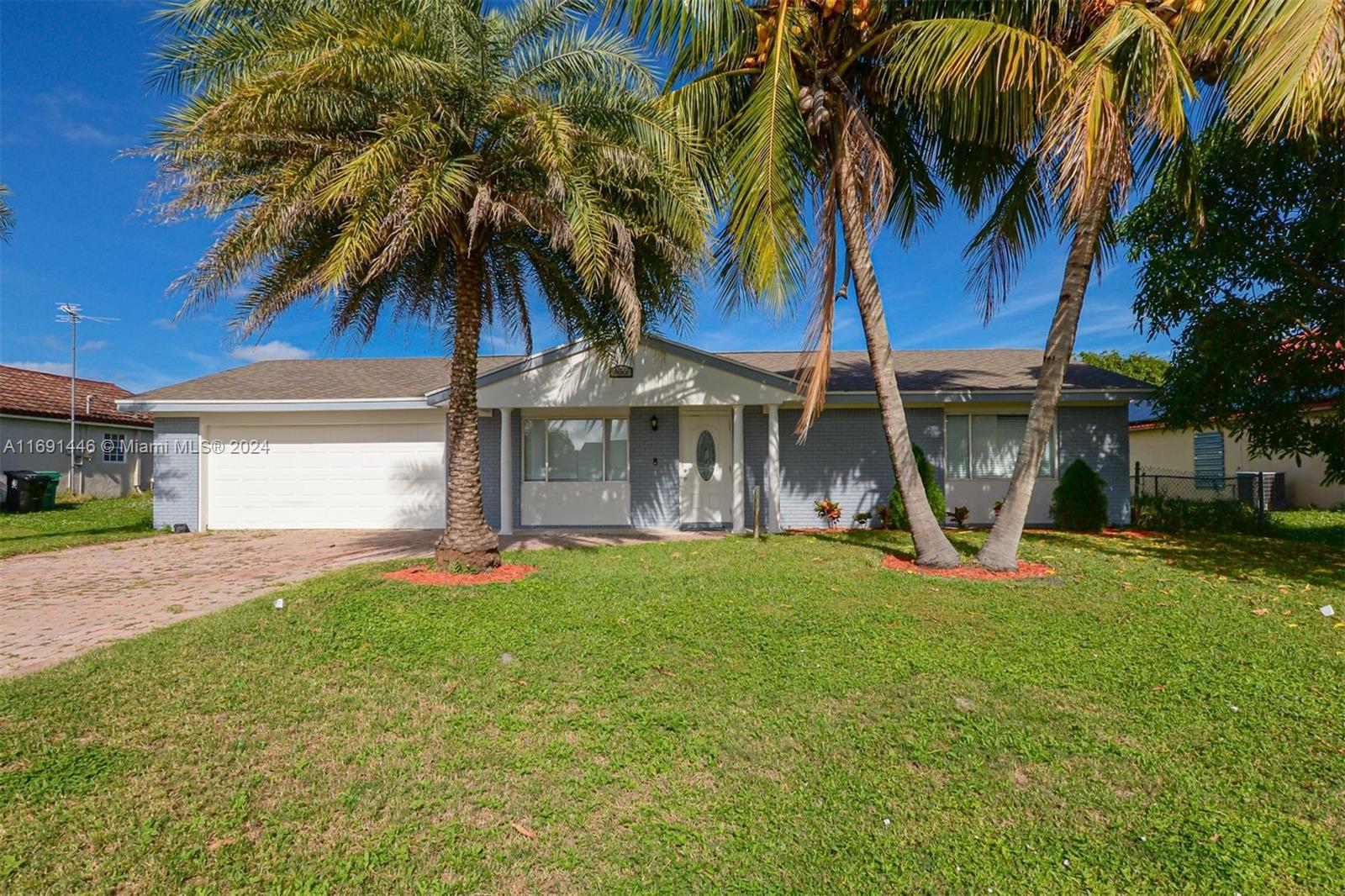 a view of a house with a yard and palm trees