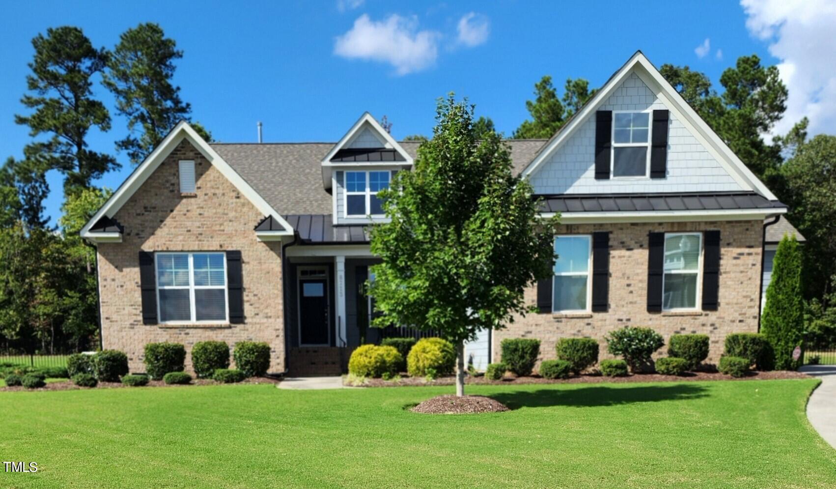 a front view of a house with a yard and trees