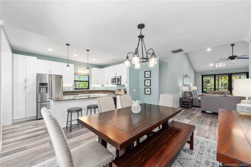 a living room with stainless steel appliances furniture a dining table and a chandelier