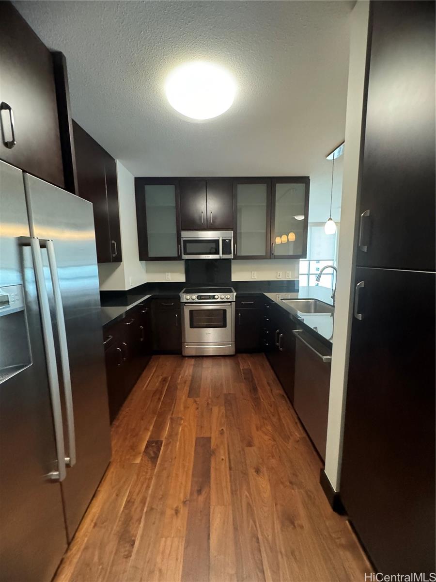 a large kitchen with wooden floor and stainless steel appliances