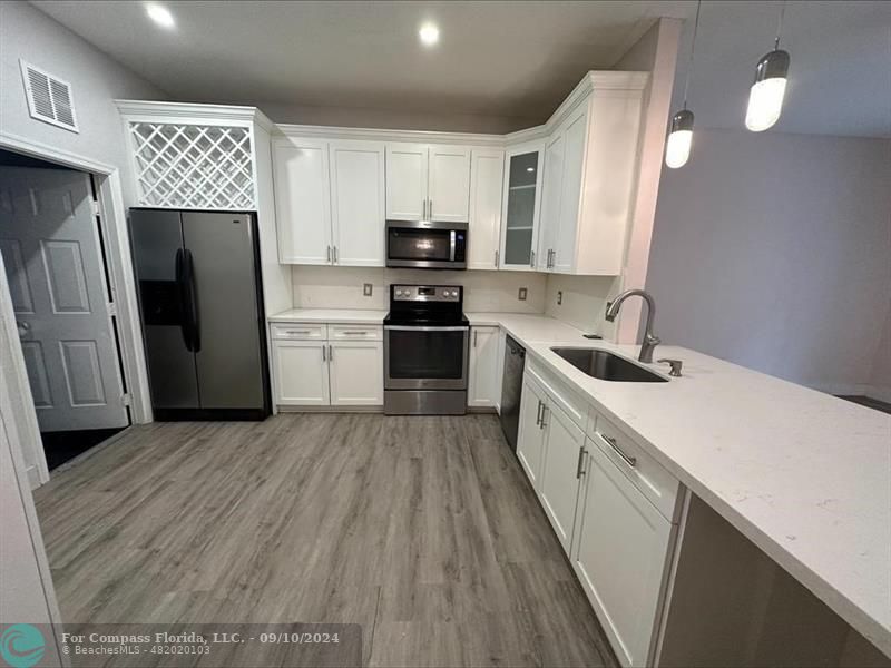 a kitchen with a sink a refrigerator a stove top oven and cabinets