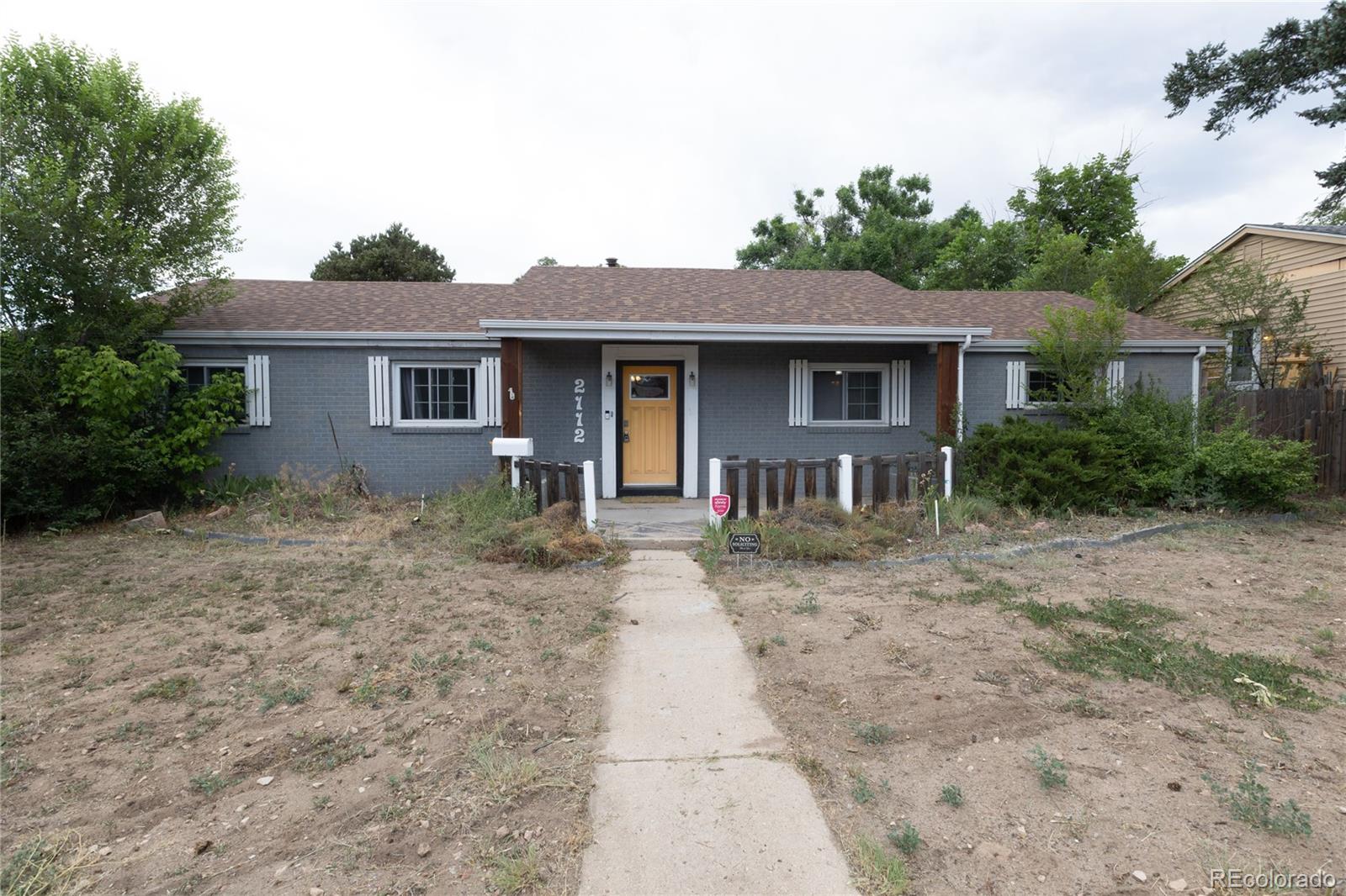 a front view of house with yard and trees in the background