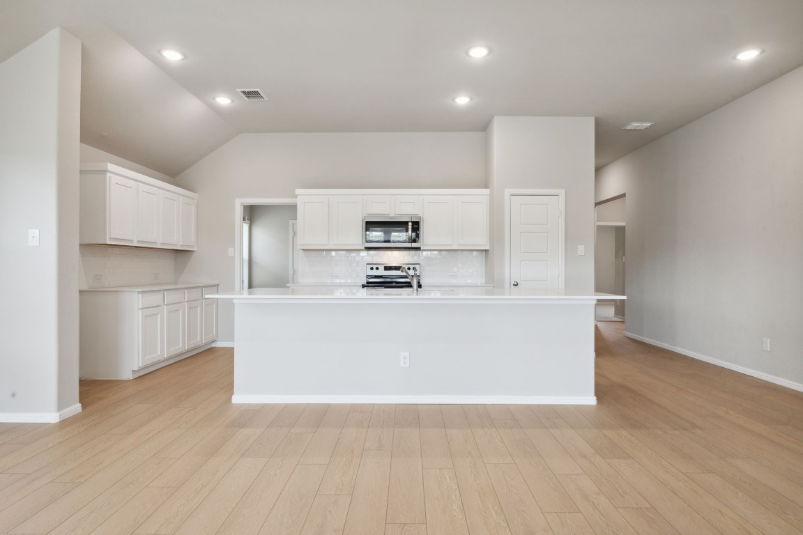 a view of kitchen with kitchen island white cabinets and stainless steel appliances