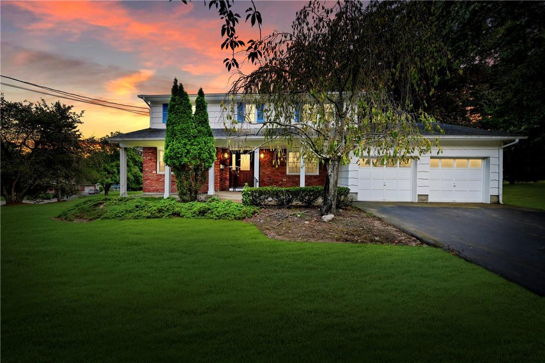 View of front of house featuring covered porch, a yard, and a garage