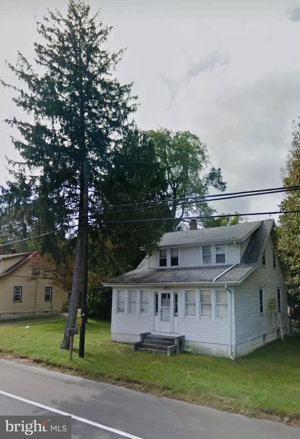 a view of a white house next to a yard with big trees