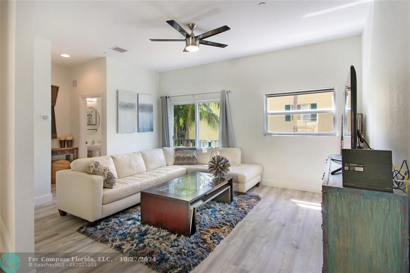 a living room with furniture a desk and chair with wooden floor