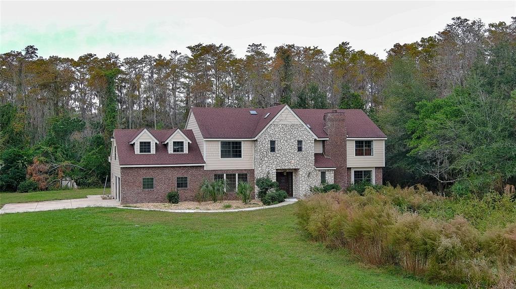 a view of a big house with a big yard and large trees