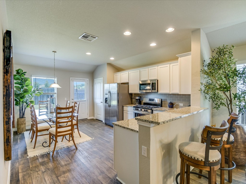 a kitchen with microwave a refrigerator and chairs