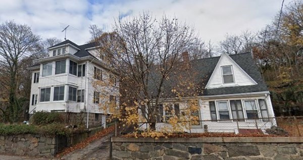 a front view of a house with large trees