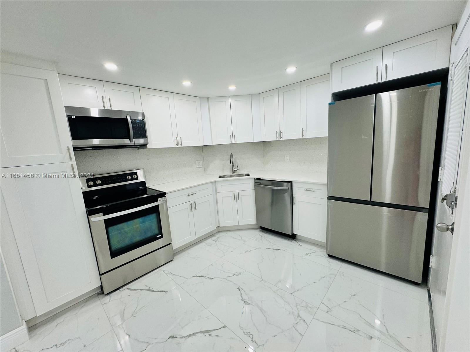 a kitchen with a refrigerator a stove top oven and cabinets