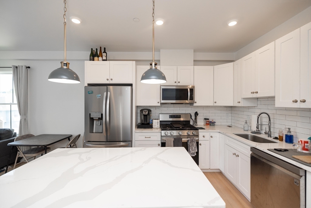 a kitchen with stainless steel appliances kitchen island granite countertop a sink a stove and cabinets