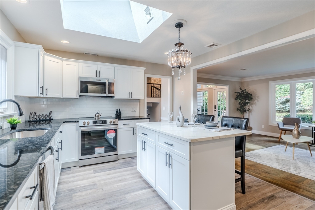 a kitchen with kitchen island granite countertop stainless steel appliances a sink stove and cabinets