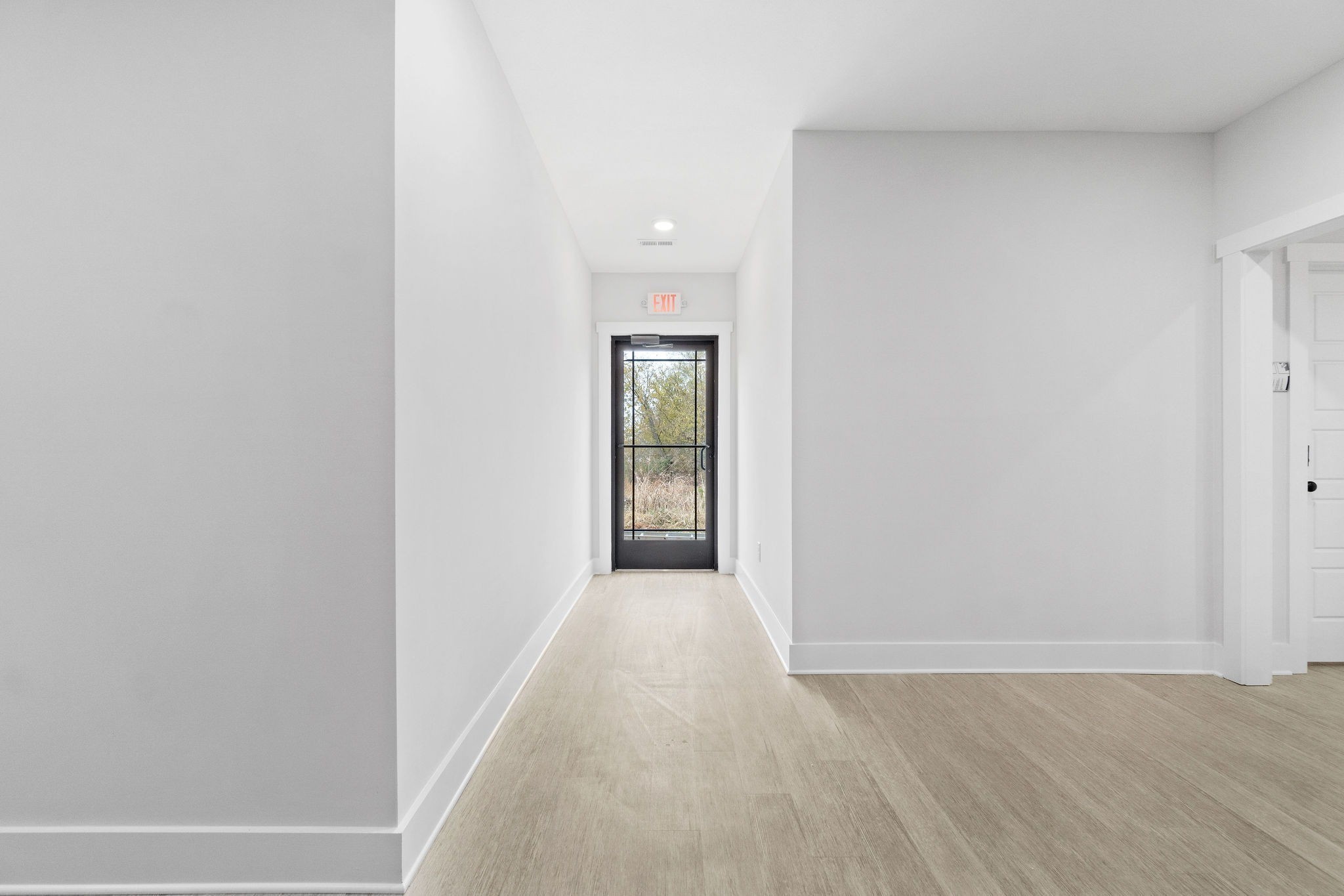 a view of a hallway with wooden floor and a window