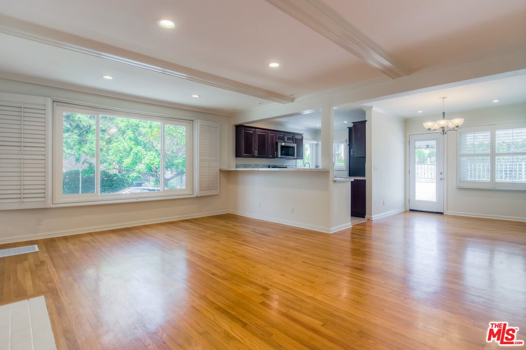 a view of empty room with wooden floor and windows