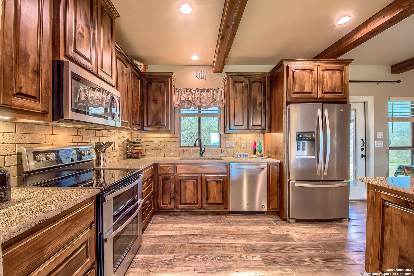 a kitchen with stainless steel appliances granite countertop a refrigerator a stove and a sink