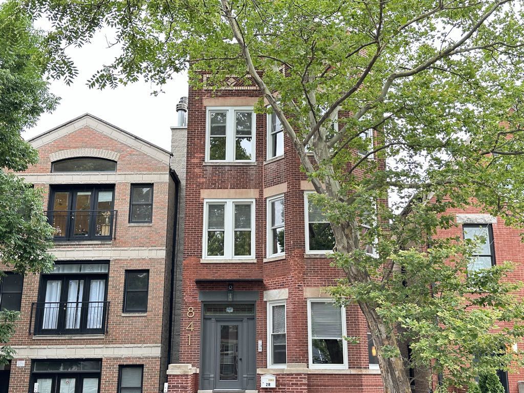 a front view of a house with a tree