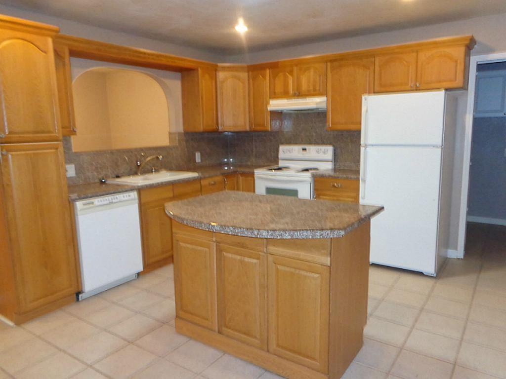 a kitchen with a refrigerator a stove top oven and cabinets