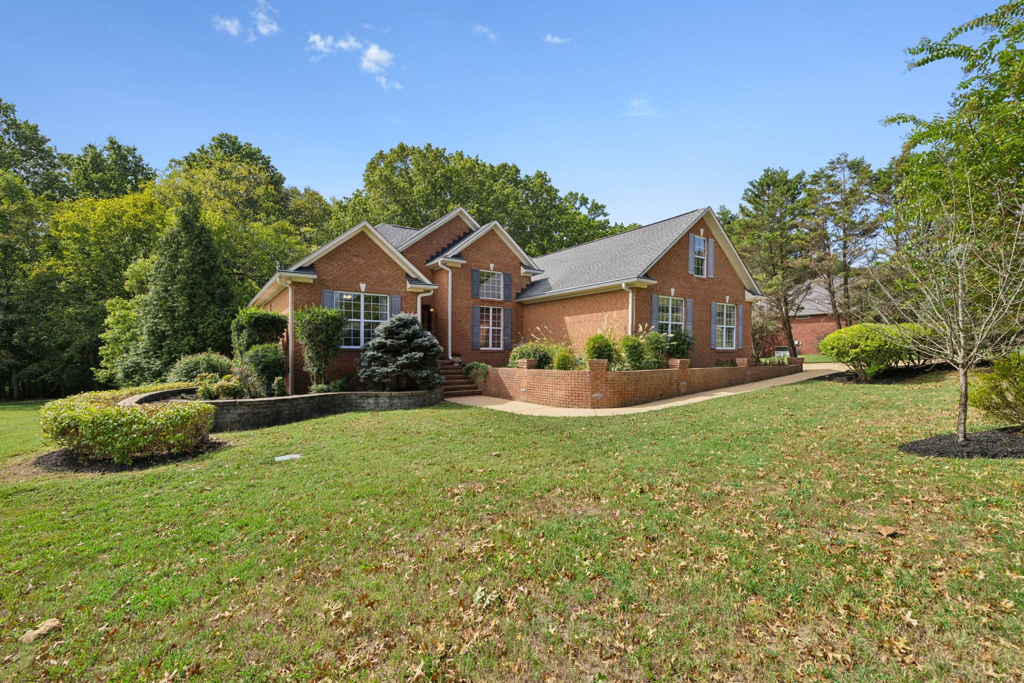 a view of a house with a big yard plants and large trees