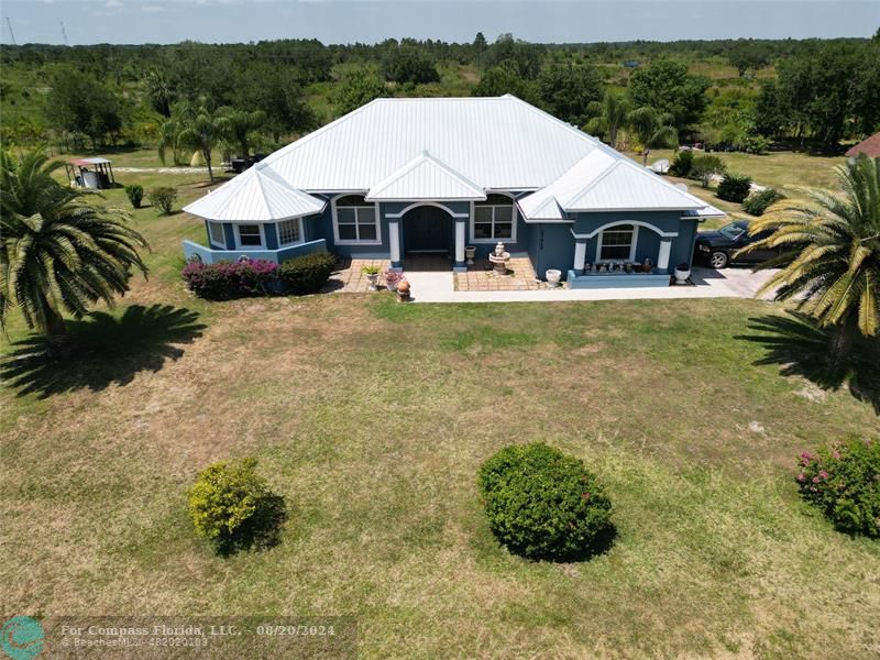 a aerial view of a white house with a big yard and large trees