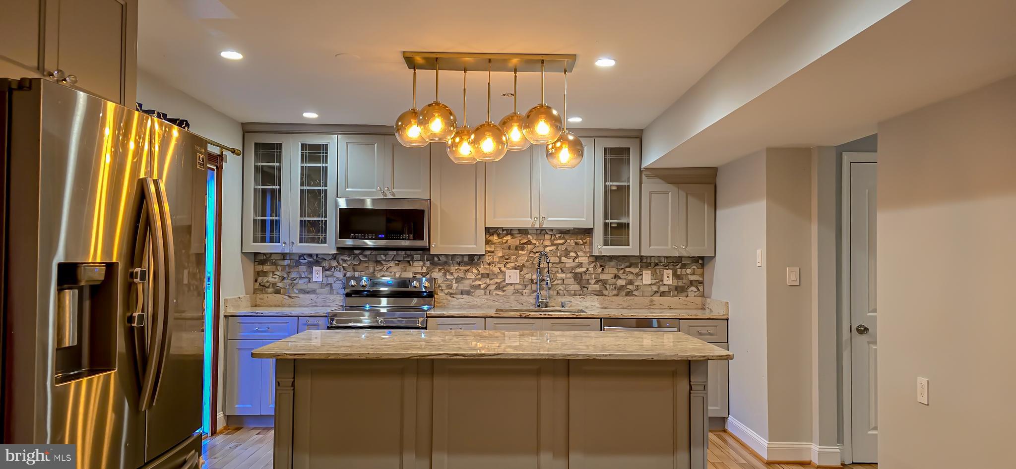 a kitchen with kitchen island granite countertop a sink and a refrigerator