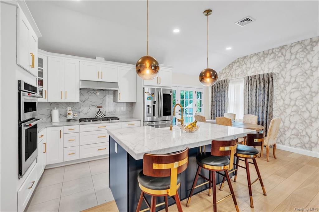 a kitchen with stainless steel appliances granite countertop a table chairs and a refrigerator