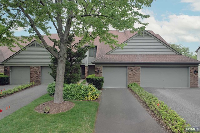 a front view of a house with a garden and trees