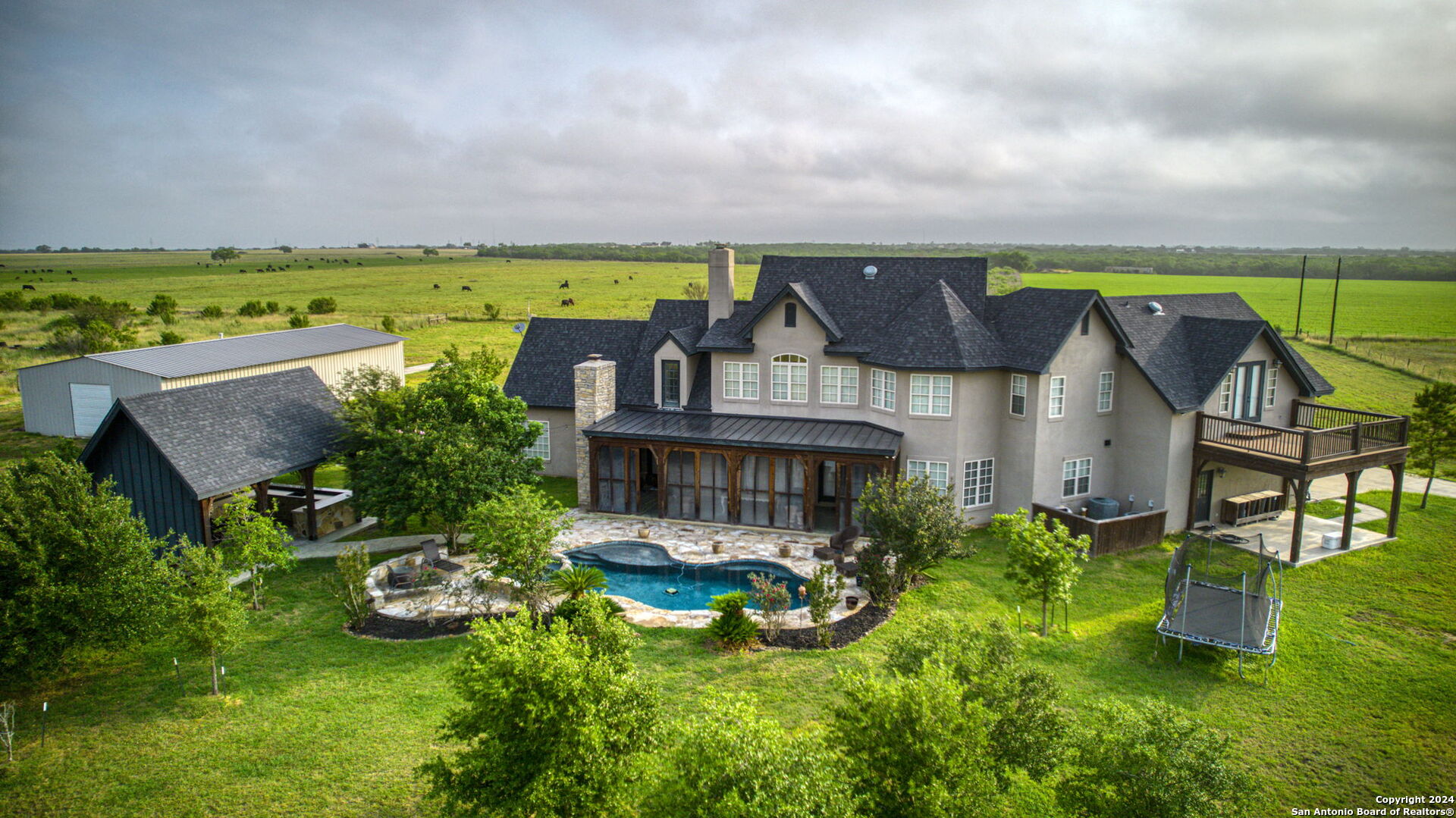 an aerial view of a house with swimming pool big yard and a large tree