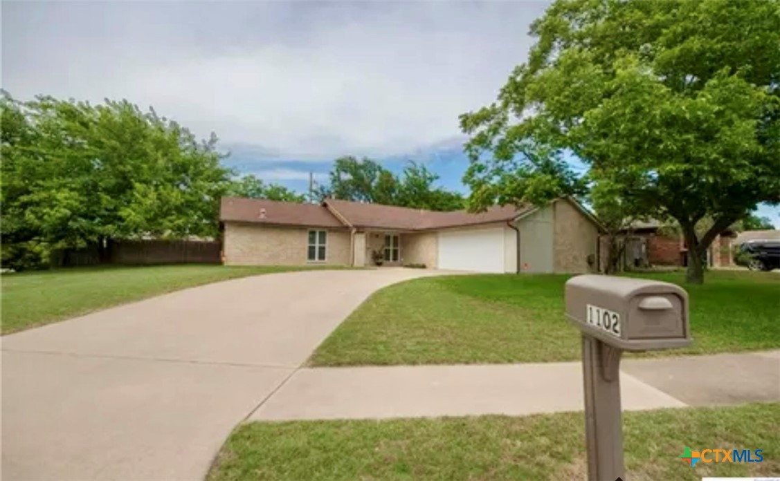 a front view of a house with a yard and a large tree