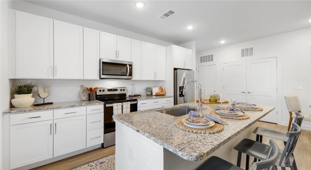 a kitchen with granite countertop stainless steel appliances stove microwave and cabinets