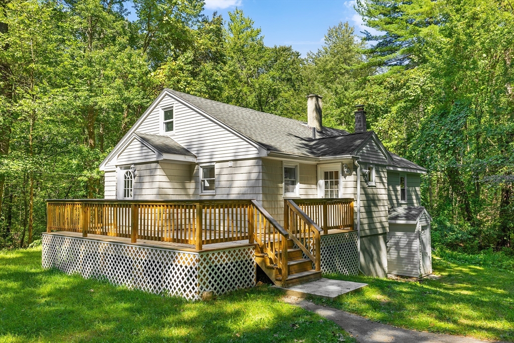 a view of a house with a wooden deck and a yard with plants