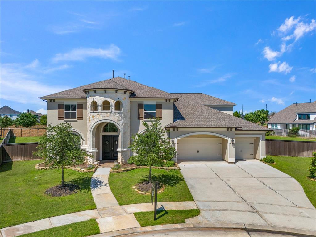 This photo captures the impressive front view of a luxury home in Katy's Cane Island. The nearly 5,000 sqft residence boasts a grand entrance with a beautifully landscaped front yard.