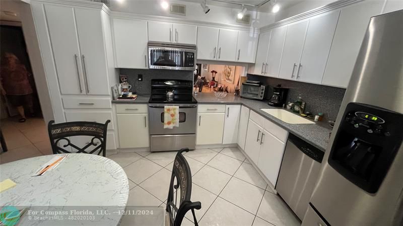 a kitchen with white cabinets and appliances