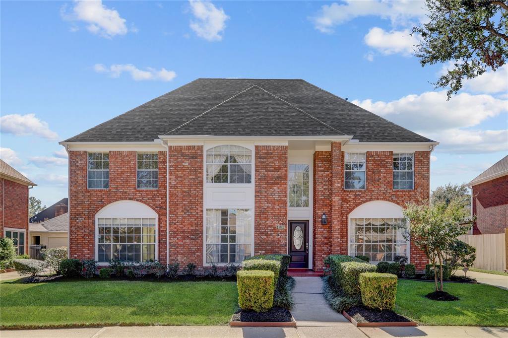 Welcome to 4526 Nassau Drive! This is a two-story brick home featuring a symmetrical facade with large windows, an arched entryway, and a steeply pitched roof. The well-manicured lawn and landscaping add to its curb appeal.