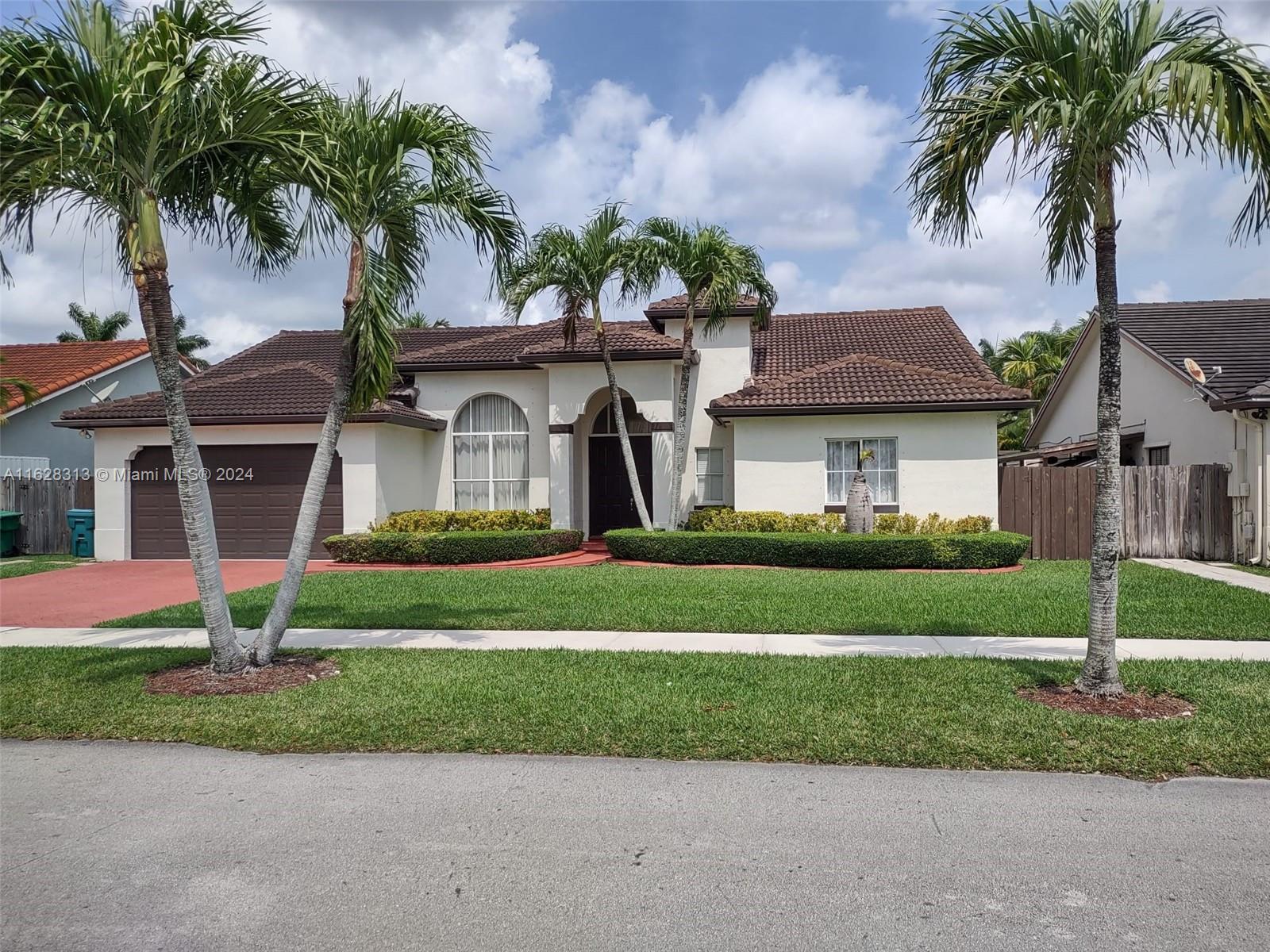 a front view of a house with a garden and palm tree