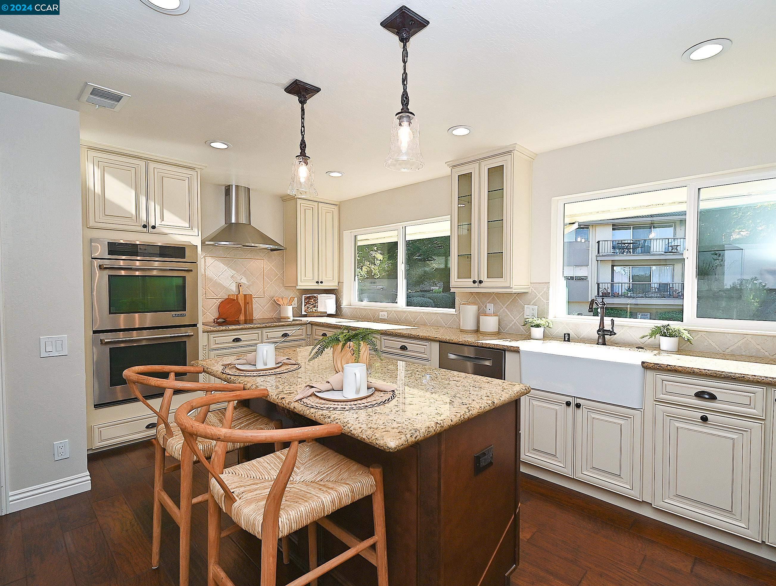 a kitchen with a stove a sink a kitchen island with chairs and wooden cabinets