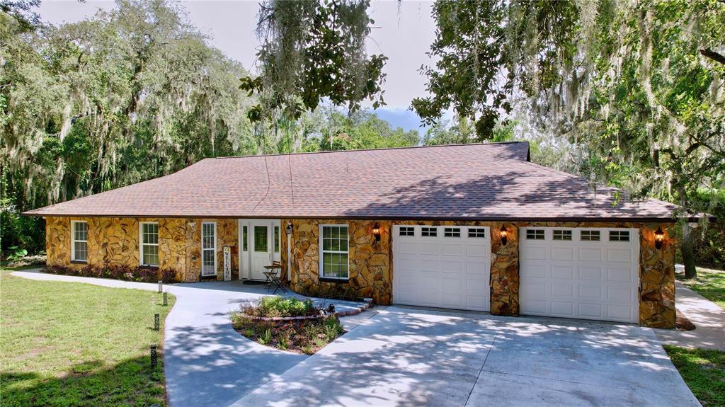 a front view of a house with a garden and a tree