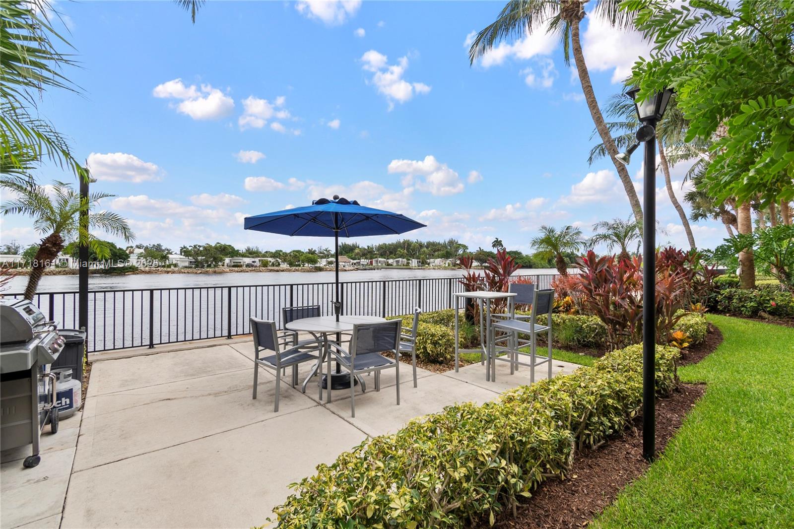 a view of a patio with couches table and chairs under an umbrella with a fire pit