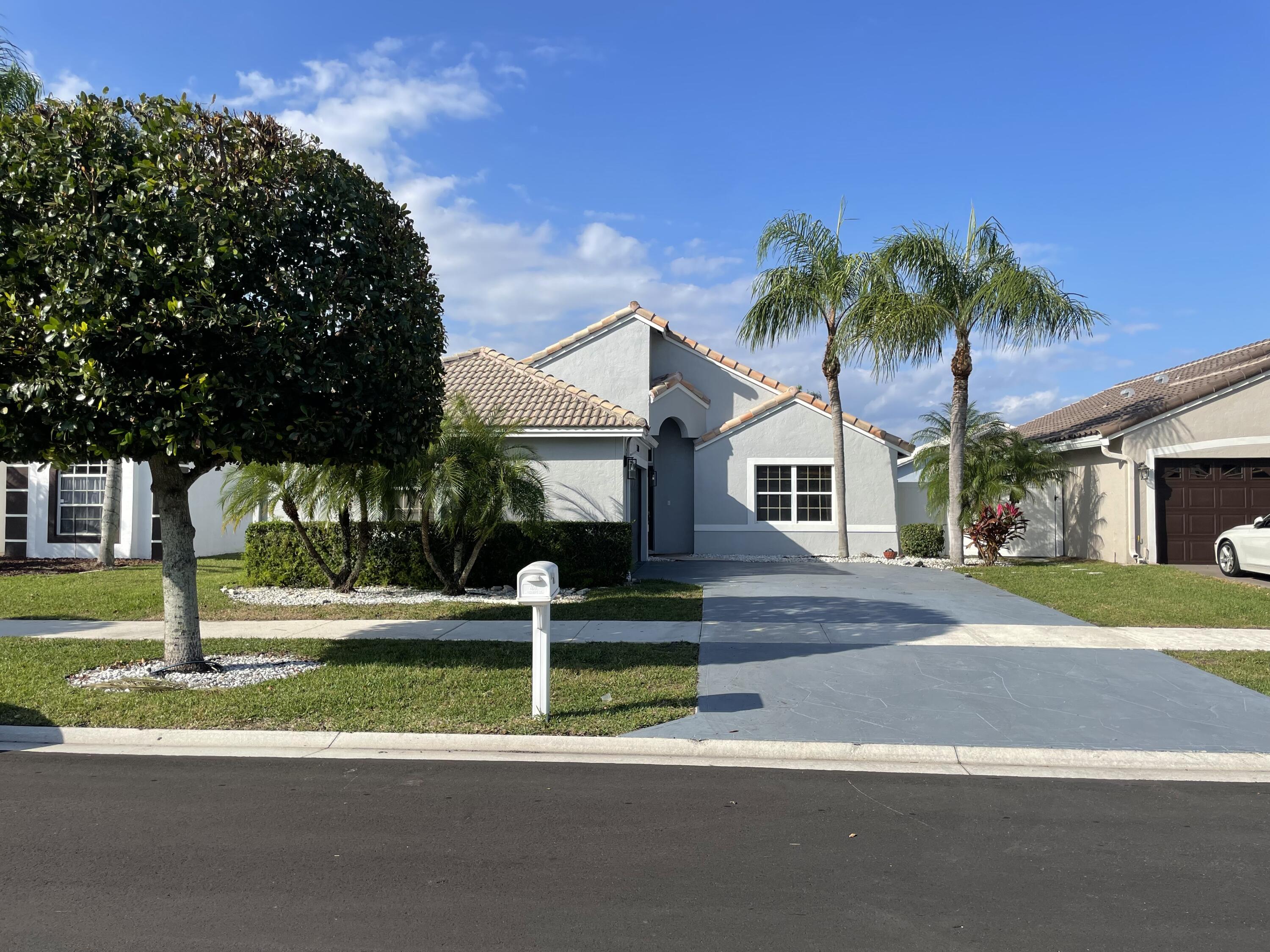 a front view of a house with a yard garage and palm tree