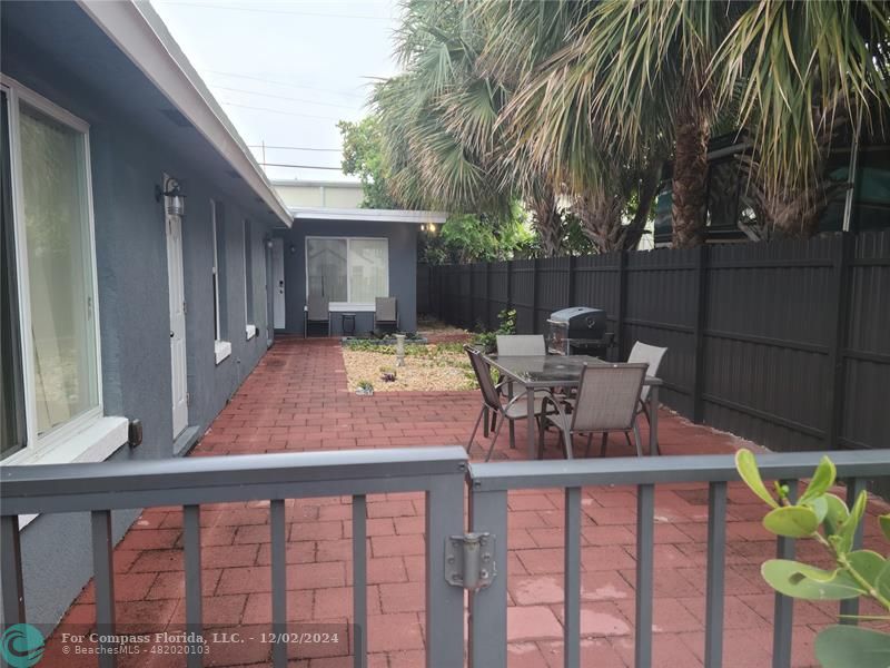 a patio with table and chairs with wooden floor and fence