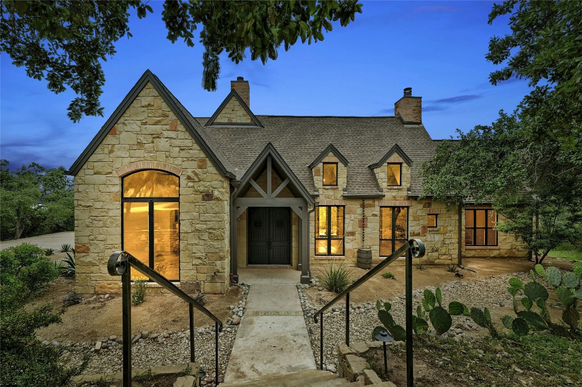 a view of a brick house with large windows and a yard