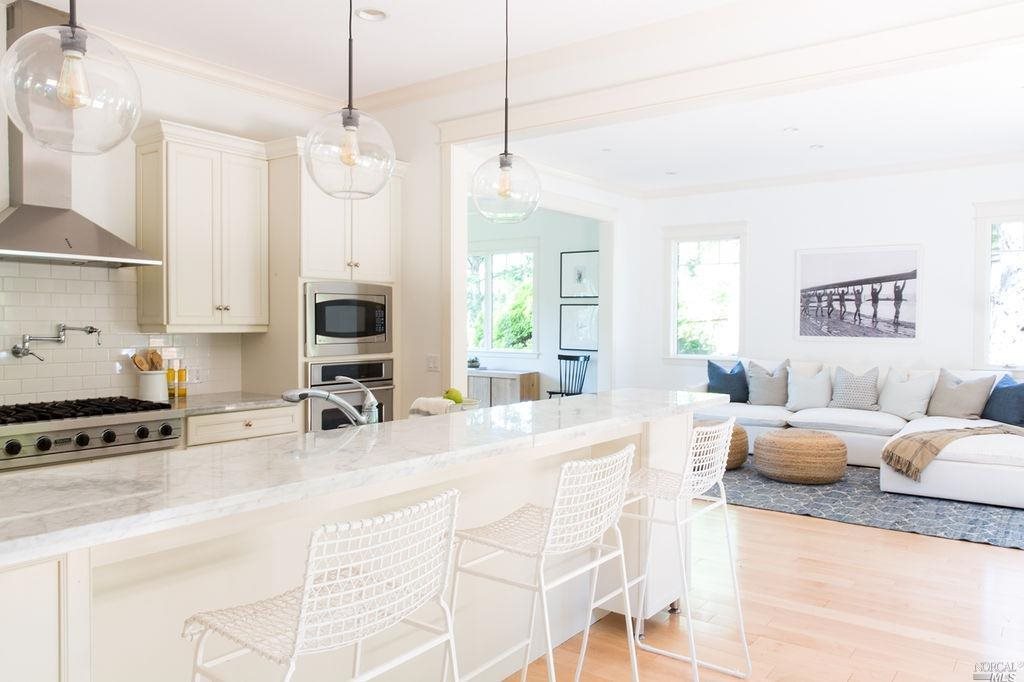 a large white kitchen with a large window a sink and a stove