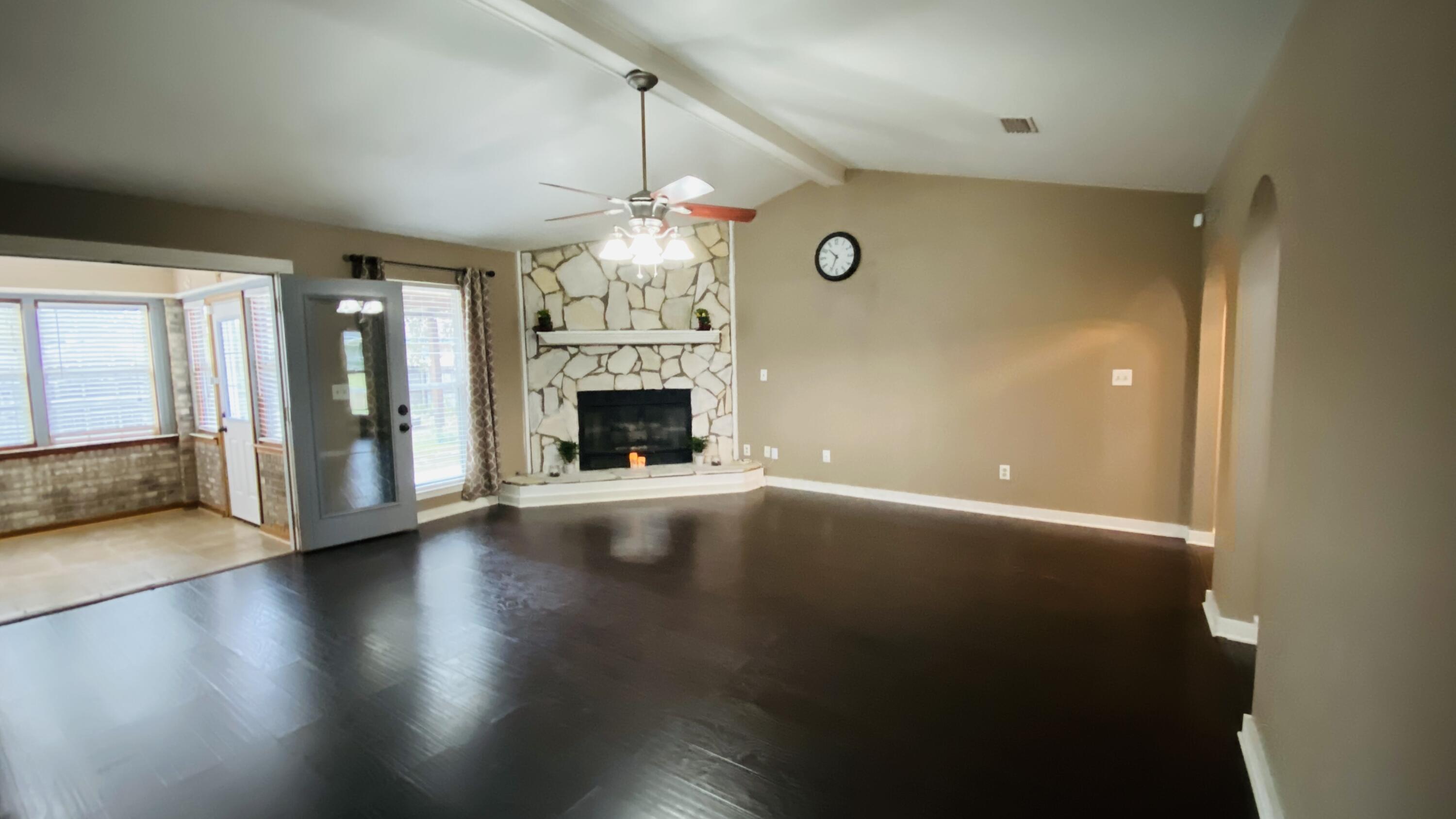 an empty room with wooden floor fireplace and chandelier