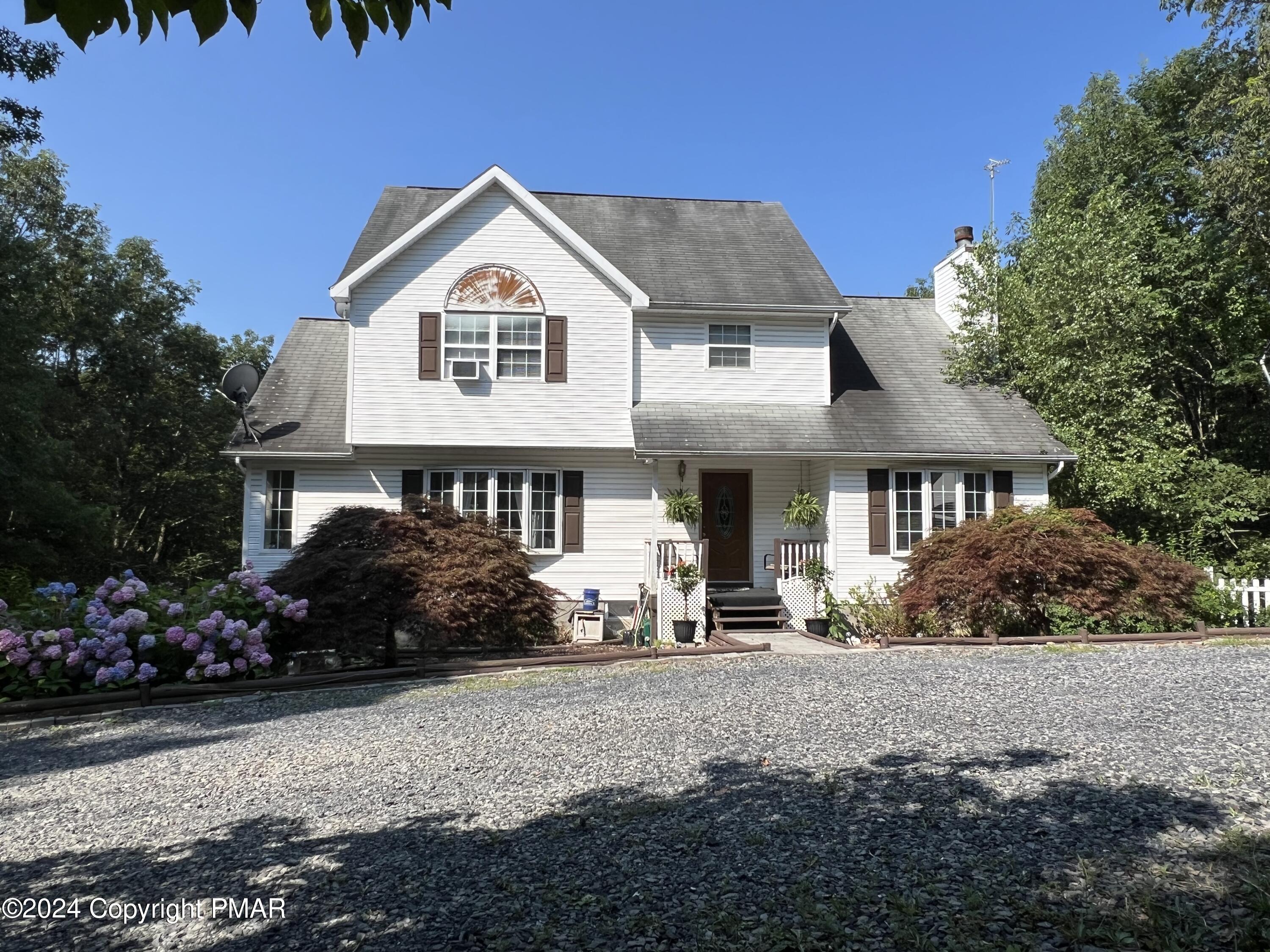 a front view of a house with a garden and trees