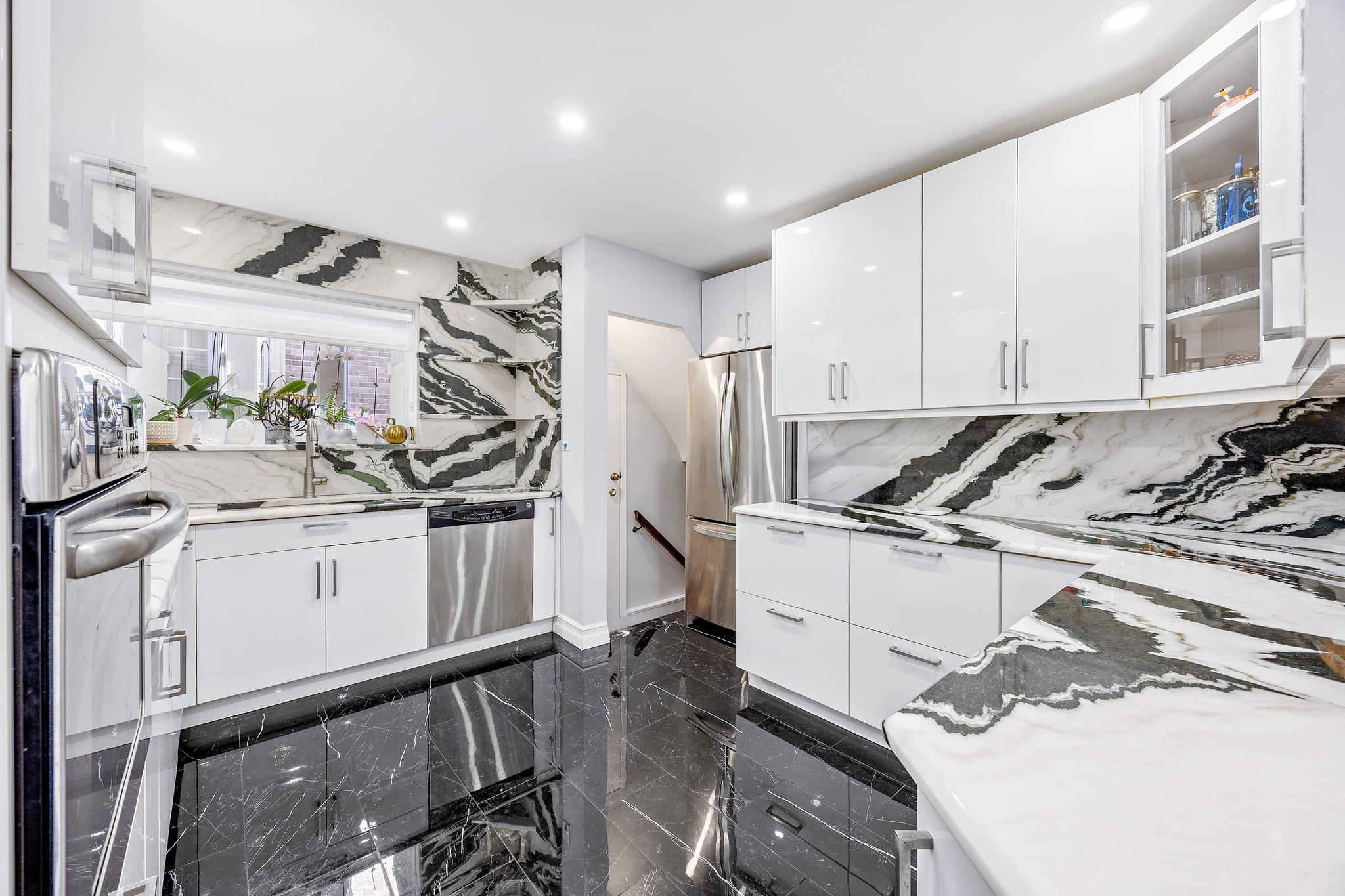 Kitchen featuring white cabinets, decorative backsplash, light stone countertops, and appliances with stainless steel finishes