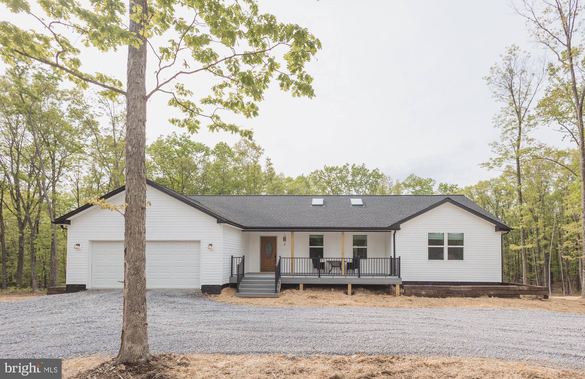 a front view of house with yard and trees in the background