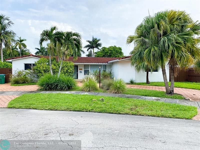 a view of a house with a yard and palm trees