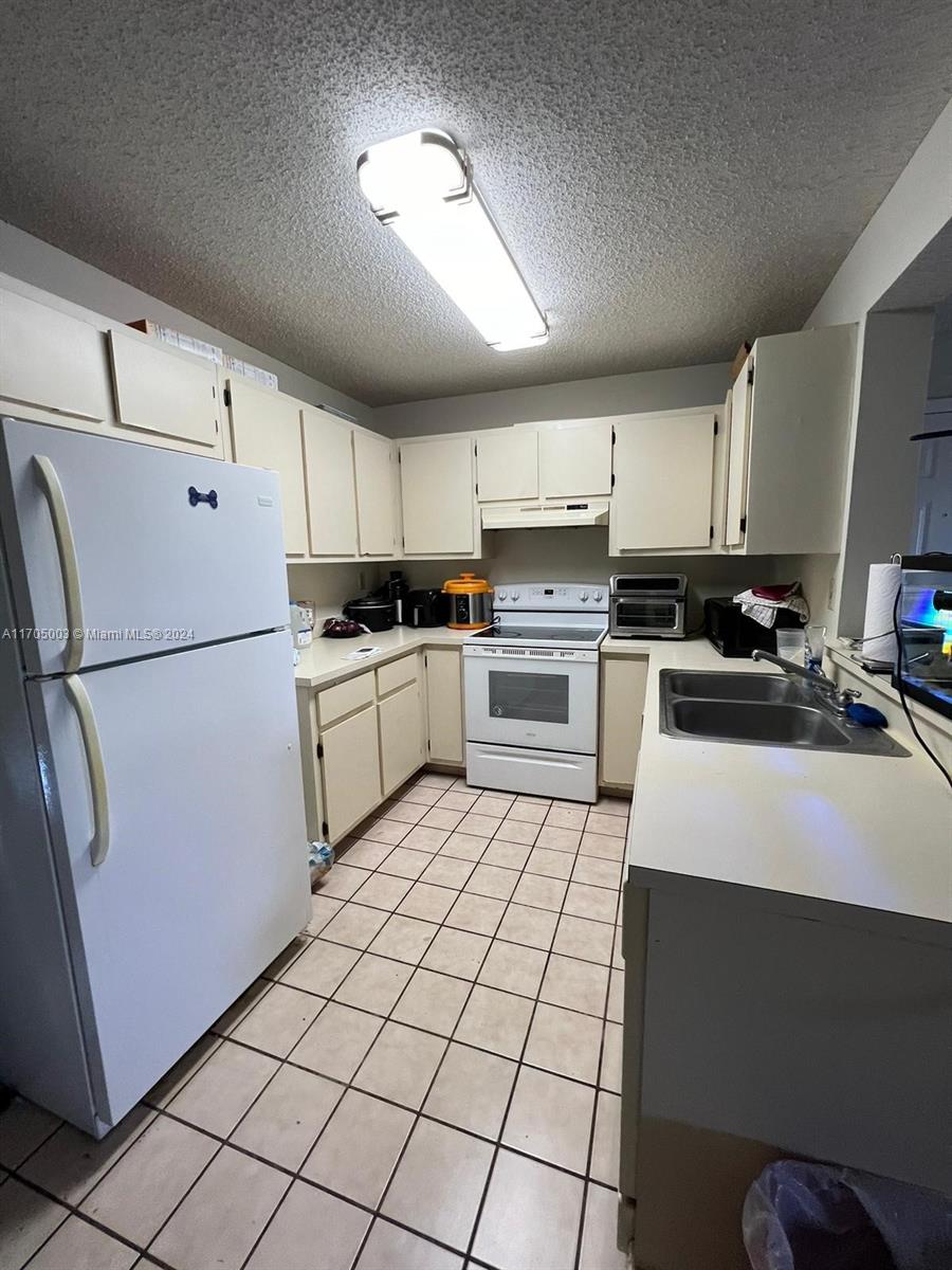 a kitchen with granite countertop a refrigerator sink stove and cabinets