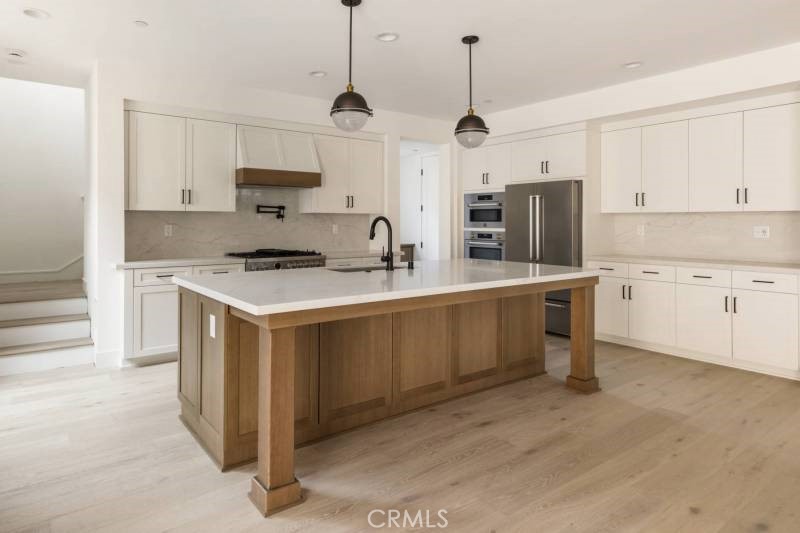 a kitchen with stainless steel appliances granite countertop a sink a stove a refrigerator and white cabinets